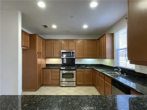 a kitchen with stainless steel appliances granite countertop a stove a sink and a refrigerator
