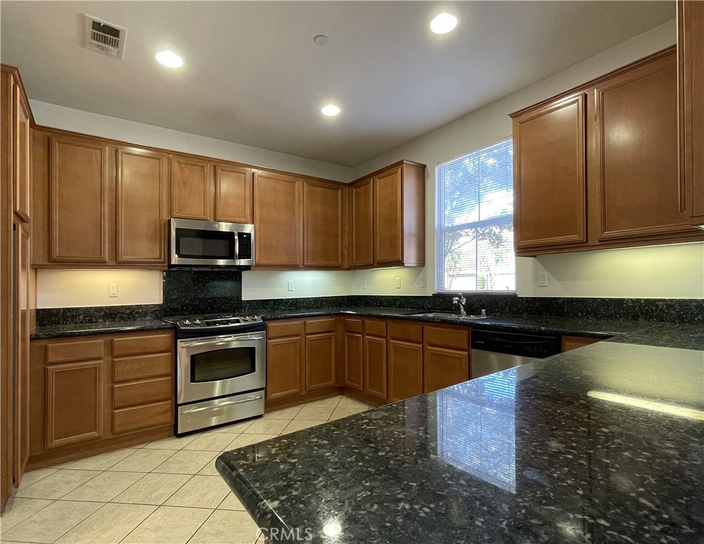 1488 Springfield Way Upland, CA 91786 - Photo 8 of 16 a kitchen with stainless steel appliances granite countertop wooden cabinets a stove top oven a sink and dishwasher