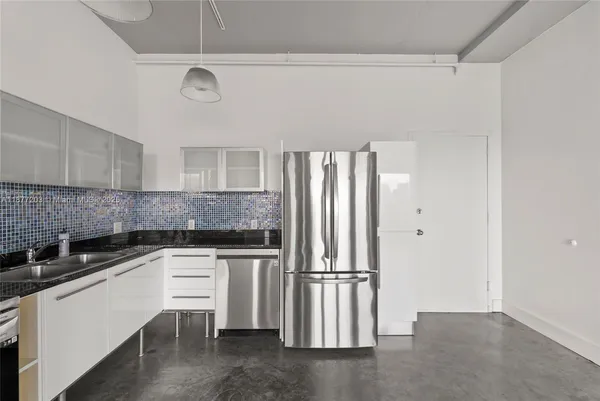 a kitchen with granite countertop a refrigerator and a sink