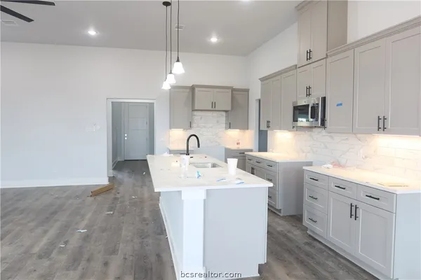 a kitchen with kitchen island a sink stainless steel appliances and white cabinets