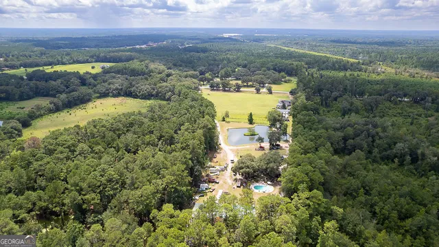 an aerial view of residential house with outdoor space and trees all around