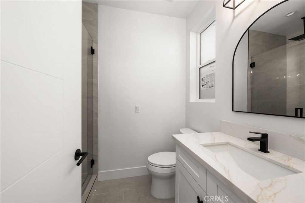 3704 Howe Street Corona, CA 92881 - Photo 15 of 26 a bathroom with a granite countertop sink toilet and mirror