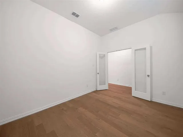 an empty room with a chandelier fan and windows