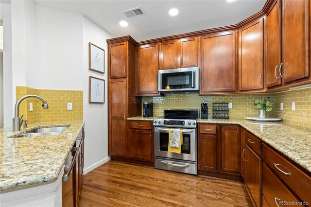 a kitchen with stainless steel appliances granite countertop wooden cabinets a stove top oven a sink and dishwasher