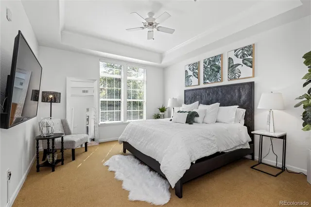 a spacious bedroom with a bed and a flat tv screen on dresser