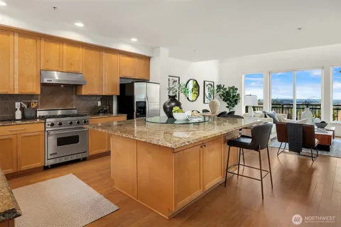 a kitchen with stainless steel appliances granite countertop a stove a sink a oven a dining table and chairs with wooden floor