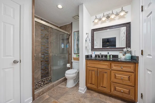 a spacious bathroom with a shower toilet sink and mirror