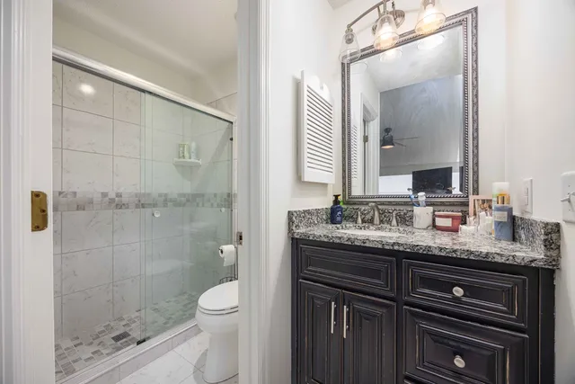 a bathroom with a granite countertop sink a toilet and a mirror