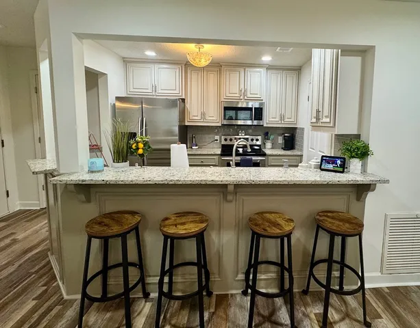 a kitchen with stainless steel appliances granite countertop a table chairs sink and cabinets