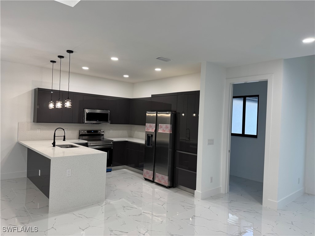 3701 East 3rd Street Lehigh Acres, FL 33936 - Photo 7 of 19 a kitchen with stainless steel appliances granite countertop a sink and a refrigerator