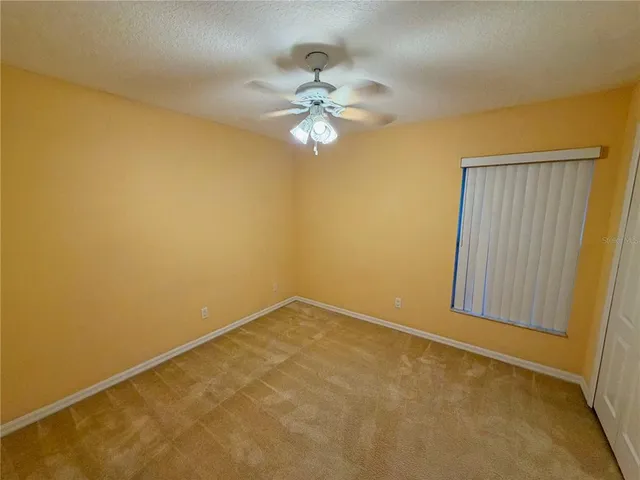 an empty room with a ceiling fan and a window