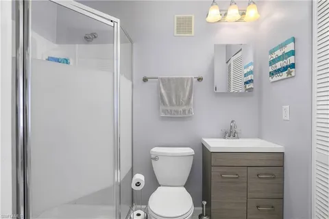 a bathroom with a toilet sink vanity and mirror