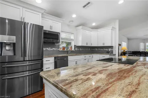 a kitchen with granite countertop stainless steel appliances and refrigerator