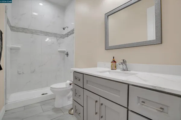 a bathroom with a granite countertop sink a toilet and shower