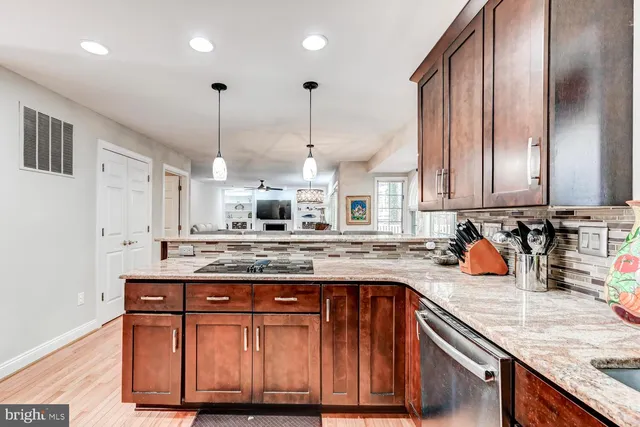a kitchen with stainless steel appliances granite countertop a stove a sink and a wooden cabinets