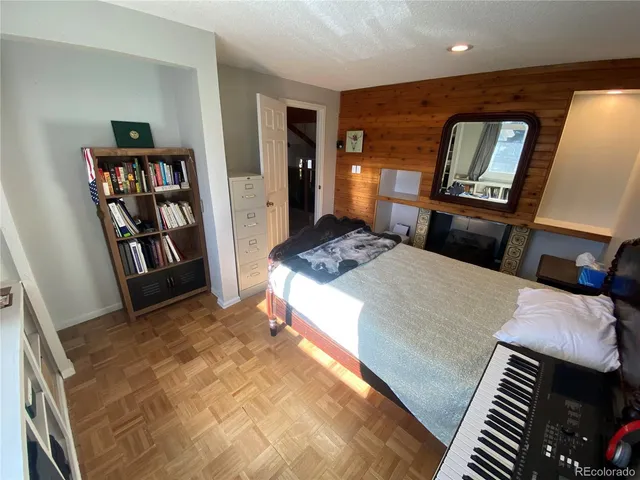 a bedroom with a bed and a bookshelf with wooden floor