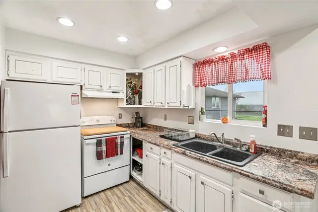 a kitchen with a refrigerator a stove top oven a sink and a window