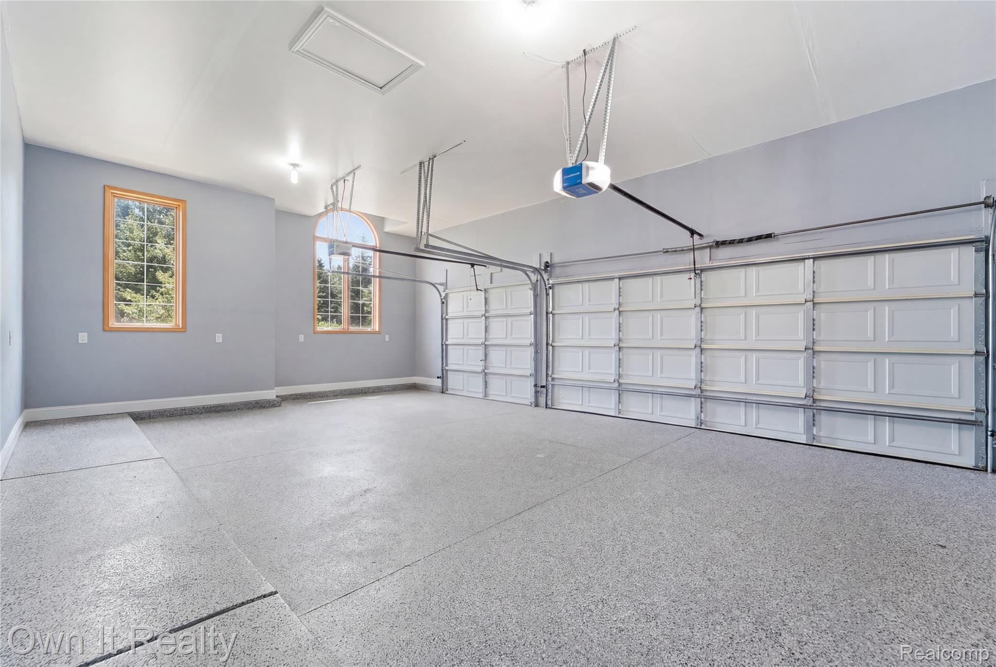 48280 Gladstone Road Canton, MI 48188 - Photo 48 of 59 Spacious multi-car garage featuring a speckled epoxy floor coating, two overhead garage doors with automatic openers, two large wood-framed windows, and a high ceiling with recessed lighting and a pull-down attic access panel