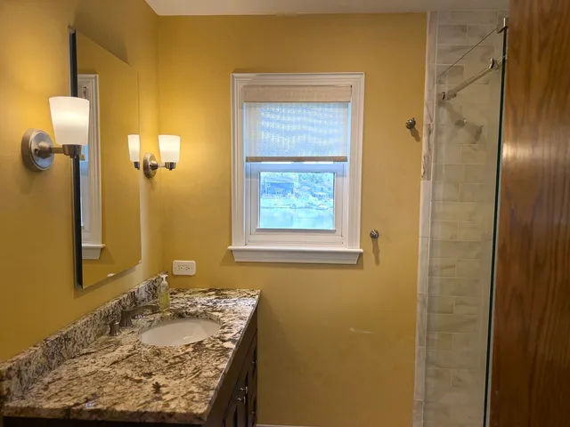 a bathroom with a granite countertop sink a bathtub and shower