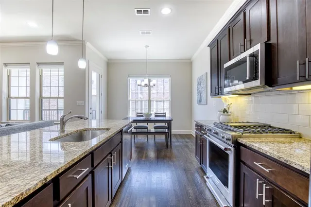 a kitchen with granite countertop a stove a sink and wooden cabinets