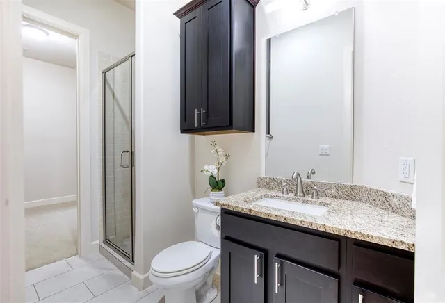 a bathroom with a granite countertop sink toilet and mirror