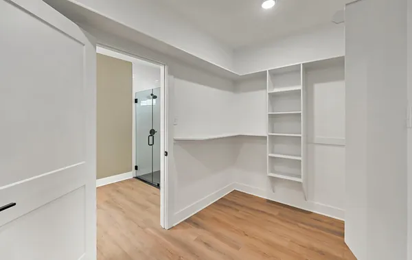 a view of an empty room with wooden floor and closet