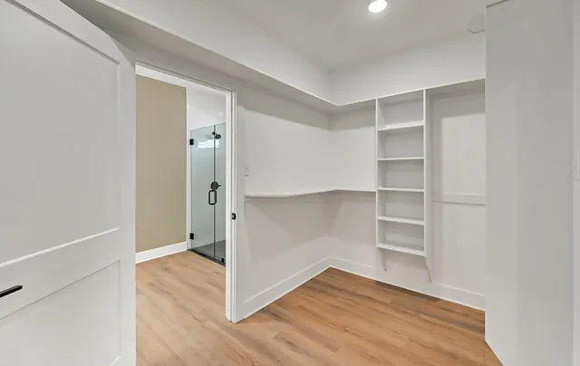 a view of an empty room with wooden floor and closet