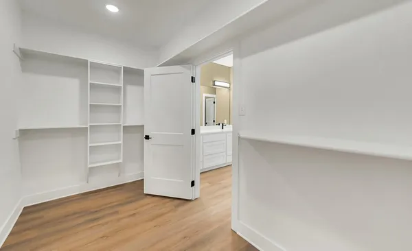 a view of an empty room with cabinet and wooden floor