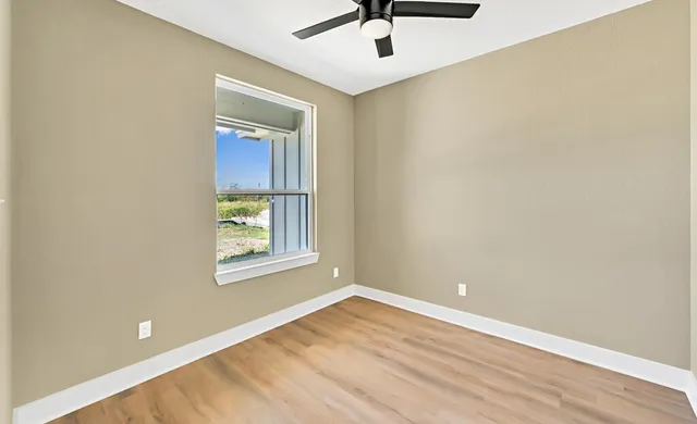 an empty room with a window and a ceiling fan