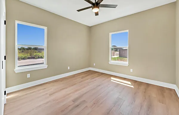 a view of an empty room with a window and wooden floor