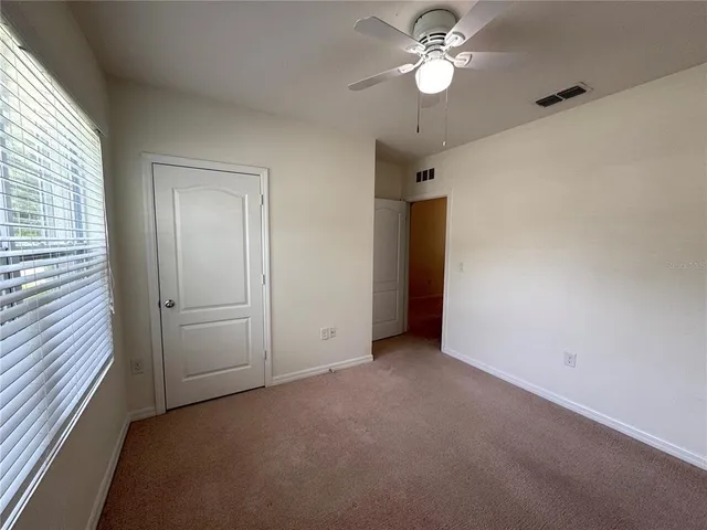 an empty room with closet and a ceiling fan