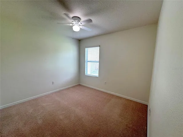 an empty room with a chandelier fan and windows