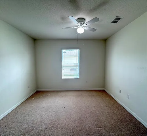 en empty room with windows and chandelier fan