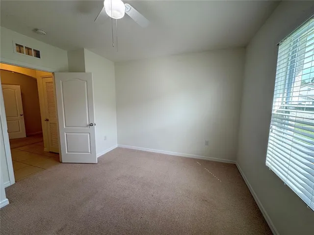 en empty room with windows and chandelier fan