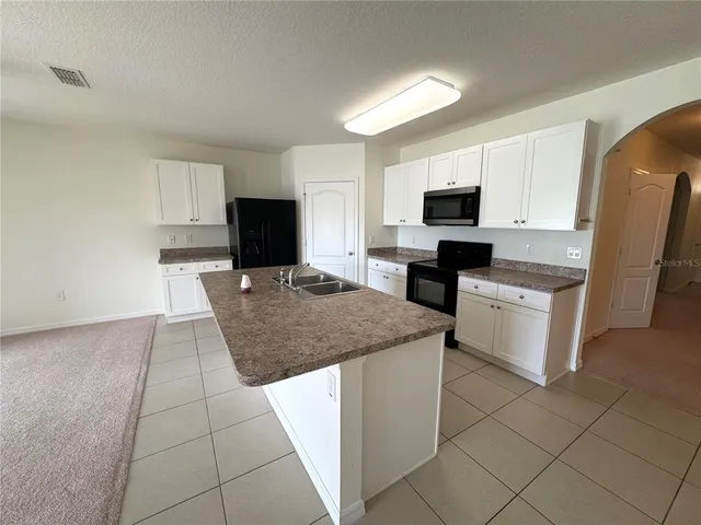 a kitchen with kitchen island granite countertop a stove top oven a sink a counter top space and cabinets