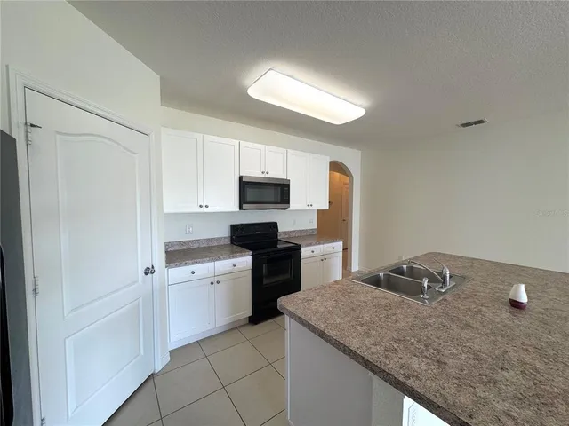 a kitchen with granite countertop white cabinets and stainless steel appliances