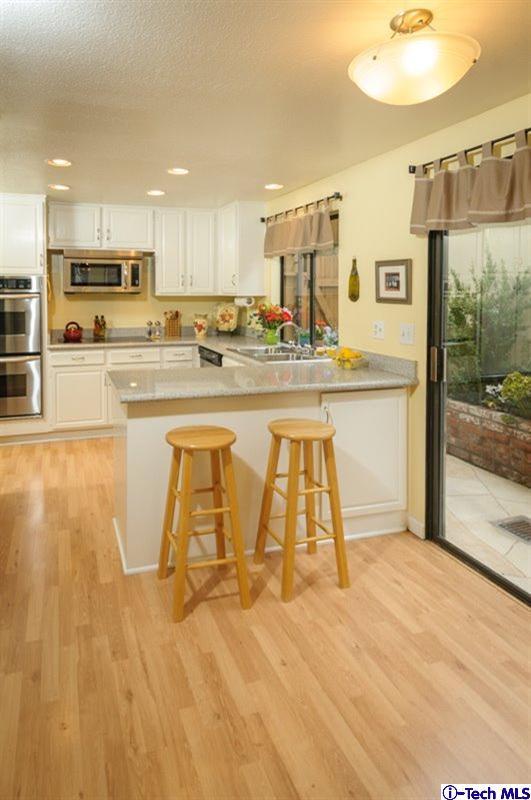 1445 Valley View Road, Unit 5 Glendale, CA 91202 - Photo 12 of 19 a large white kitchen with wooden floor and stainless steel appliances