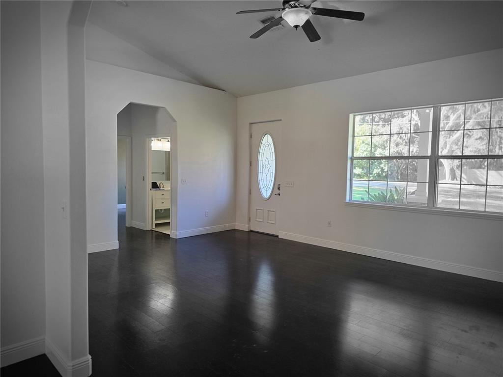 27410 Yalaha Cut Off Road Yalaha, FL 34797 - Photo 6 of 22 an empty room with wooden floor chandelier fan and windows