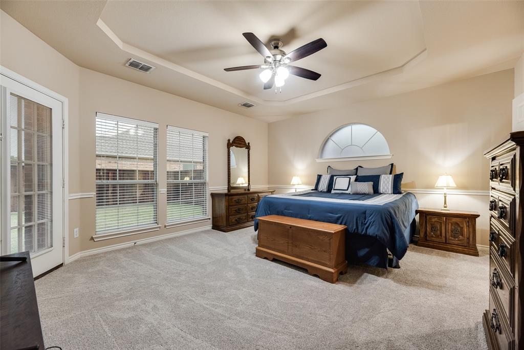 11920 Vienna Apple Road Fort Worth, TX 76244 - Photo 20 of 40 Primary bedroom with new carpet, tiered ceiling, door to the back patio and ensuite bathroom at 11920 Vienna Apple in Villages of Woodland Springs community in North Fort Worth
