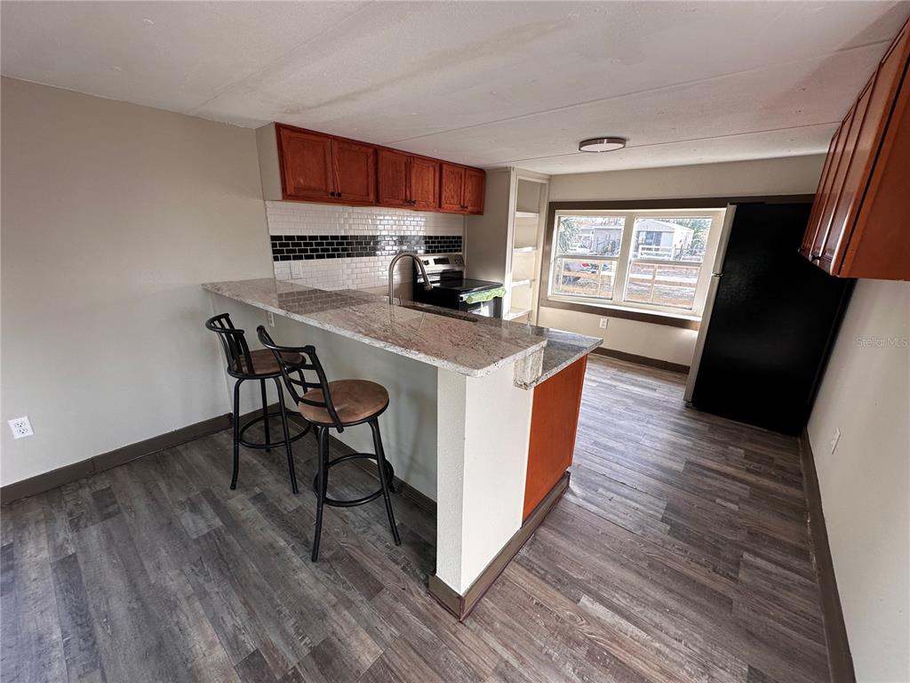 16083 Naples Street Brooksville, FL 34604 - Photo 11 of 16 a kitchen with stainless steel appliances a stove a sink a refrigerator and wooden floor