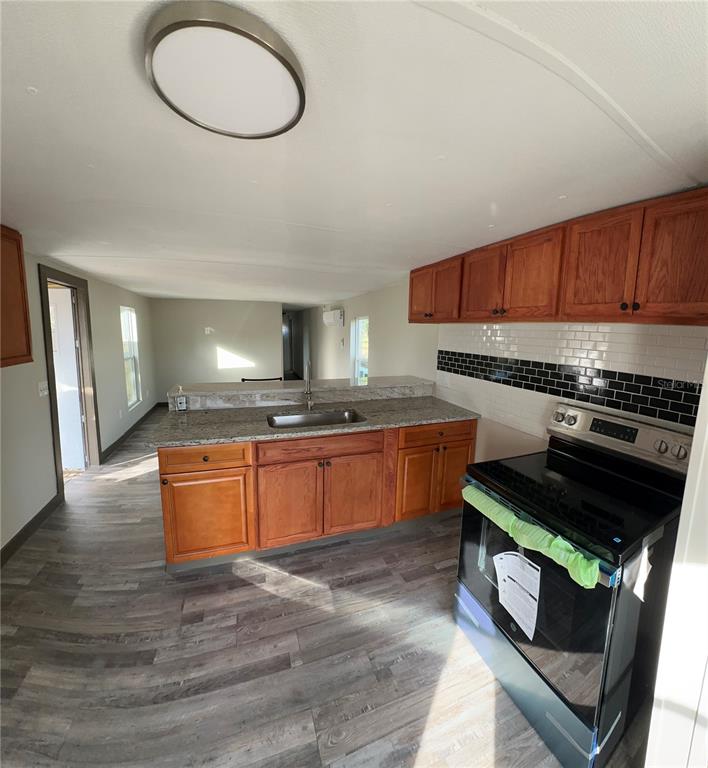 16083 Naples Street Brooksville, FL 34604 - Photo 15 of 16 a kitchen with stainless steel appliances granite countertop a stove a sink and a microwave