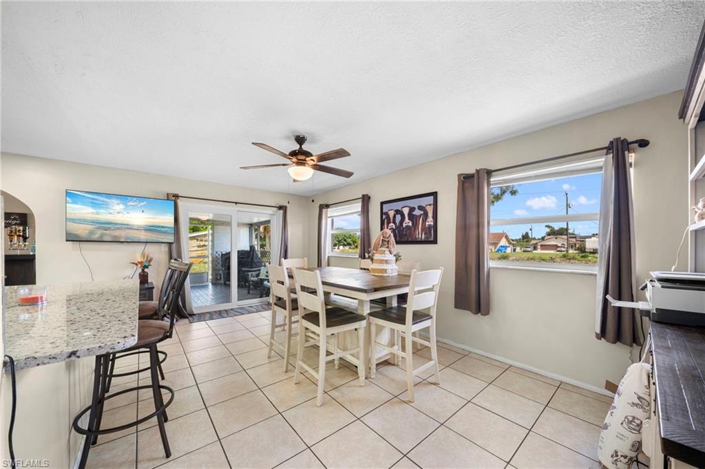 7289 Barragan Road Fort Myers, FL 33967 - Photo 7 of 18 Open concept living area featuring tile flooring, a built-in breakfast bar with a light-toned countertop, and a ceiling fan with integrated lighting