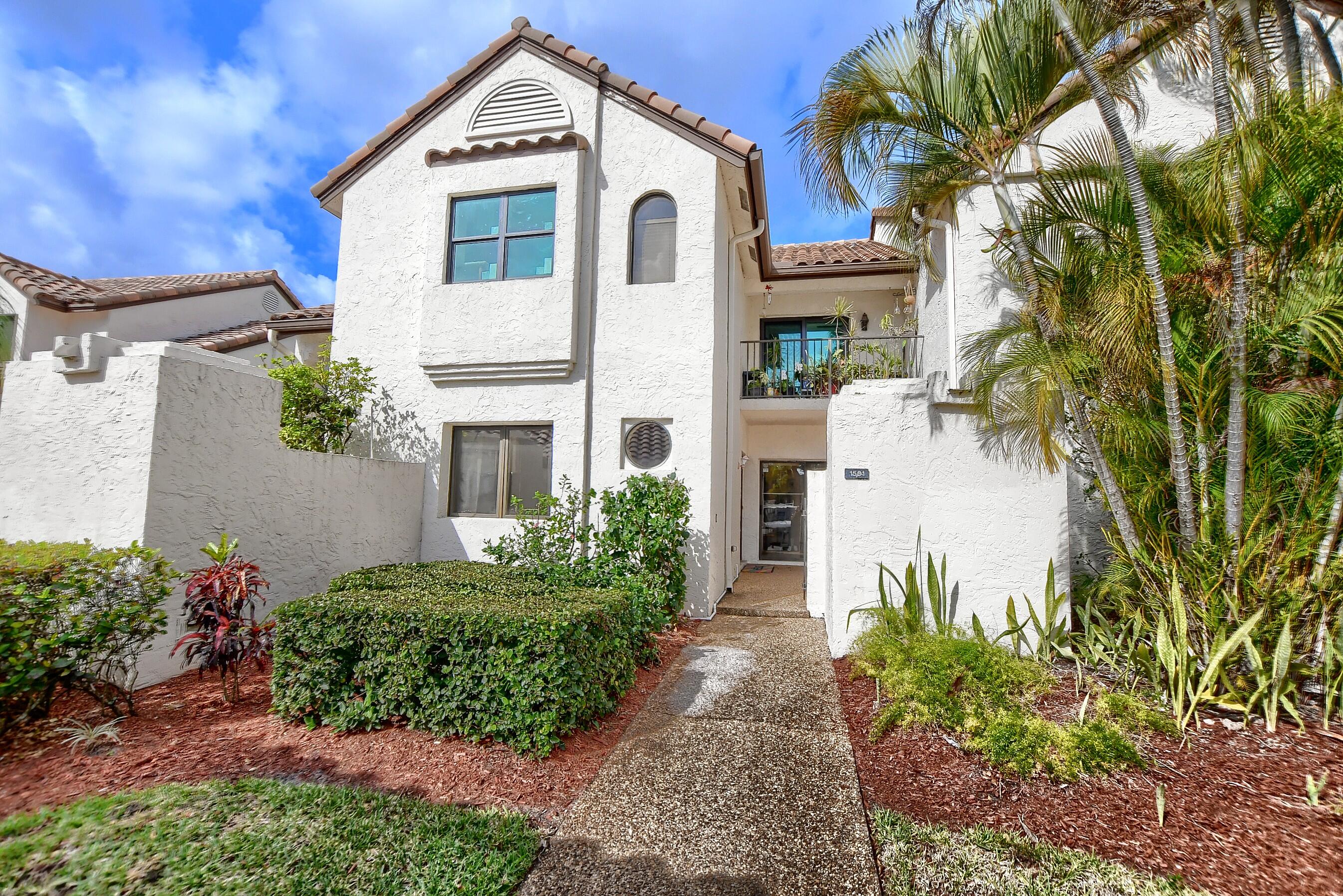 a view of a white house with a large windows and flower plants