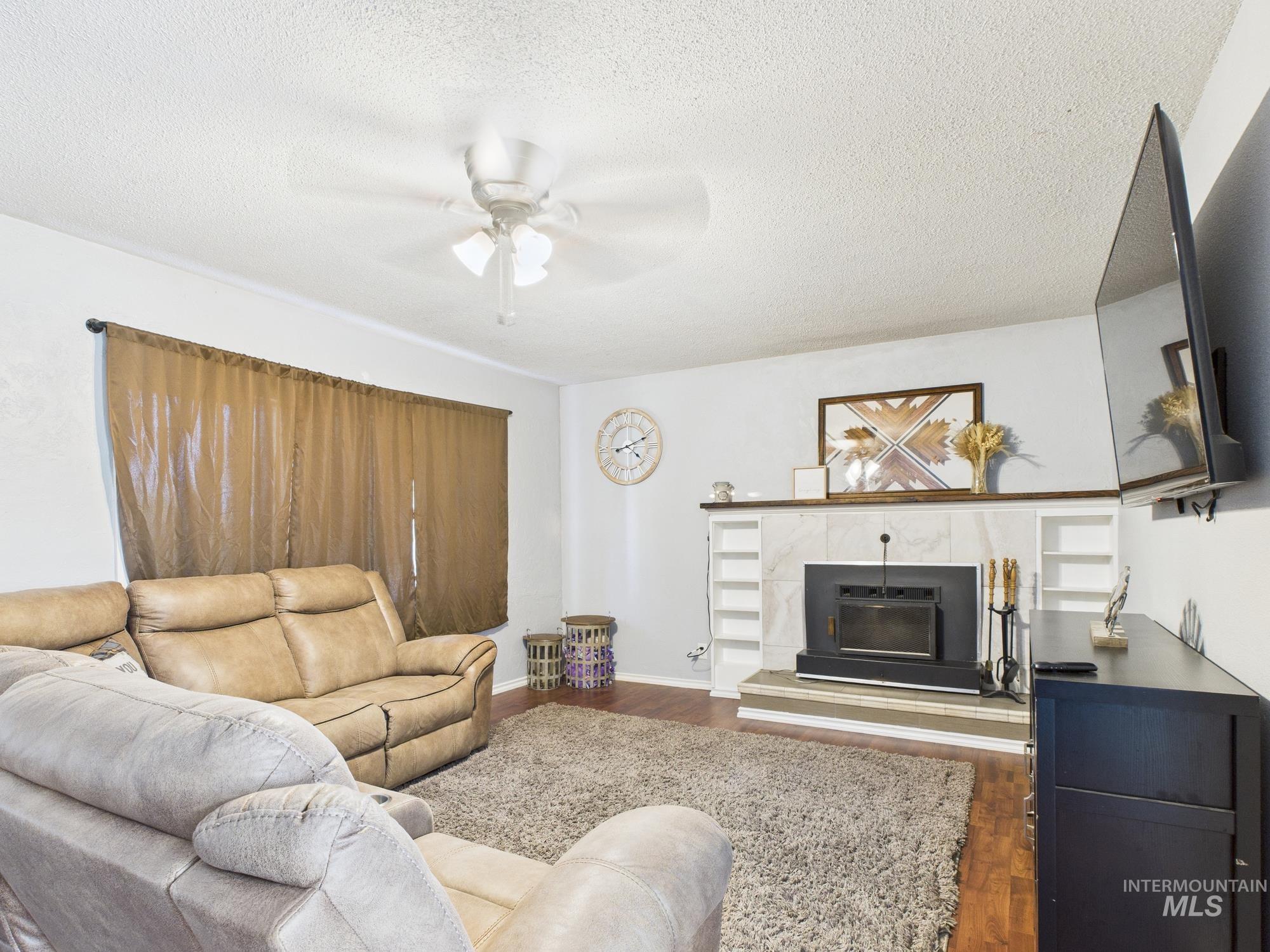 1428 Bryden Avenue Lewiston, ID 83501 - Photo 19 of 32 Living area featuring wood finished floors, ceiling fan, a textured ceiling, and a tile fireplace