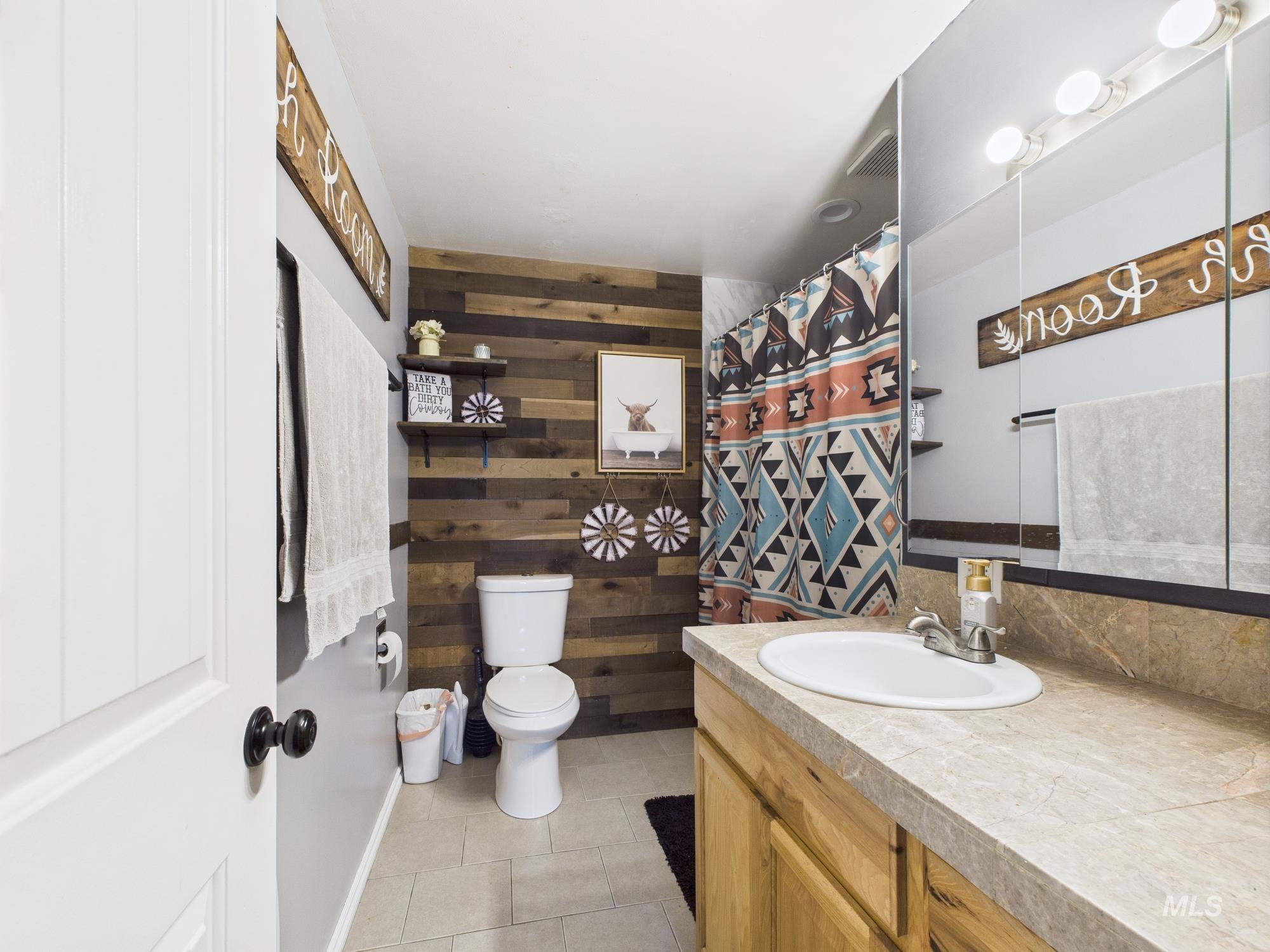 1428 Bryden Avenue Lewiston, ID 83501 - Photo 23 of 32 Bathroom with vanity, wooden walls, tile patterned flooring, and a shower with shower curtain