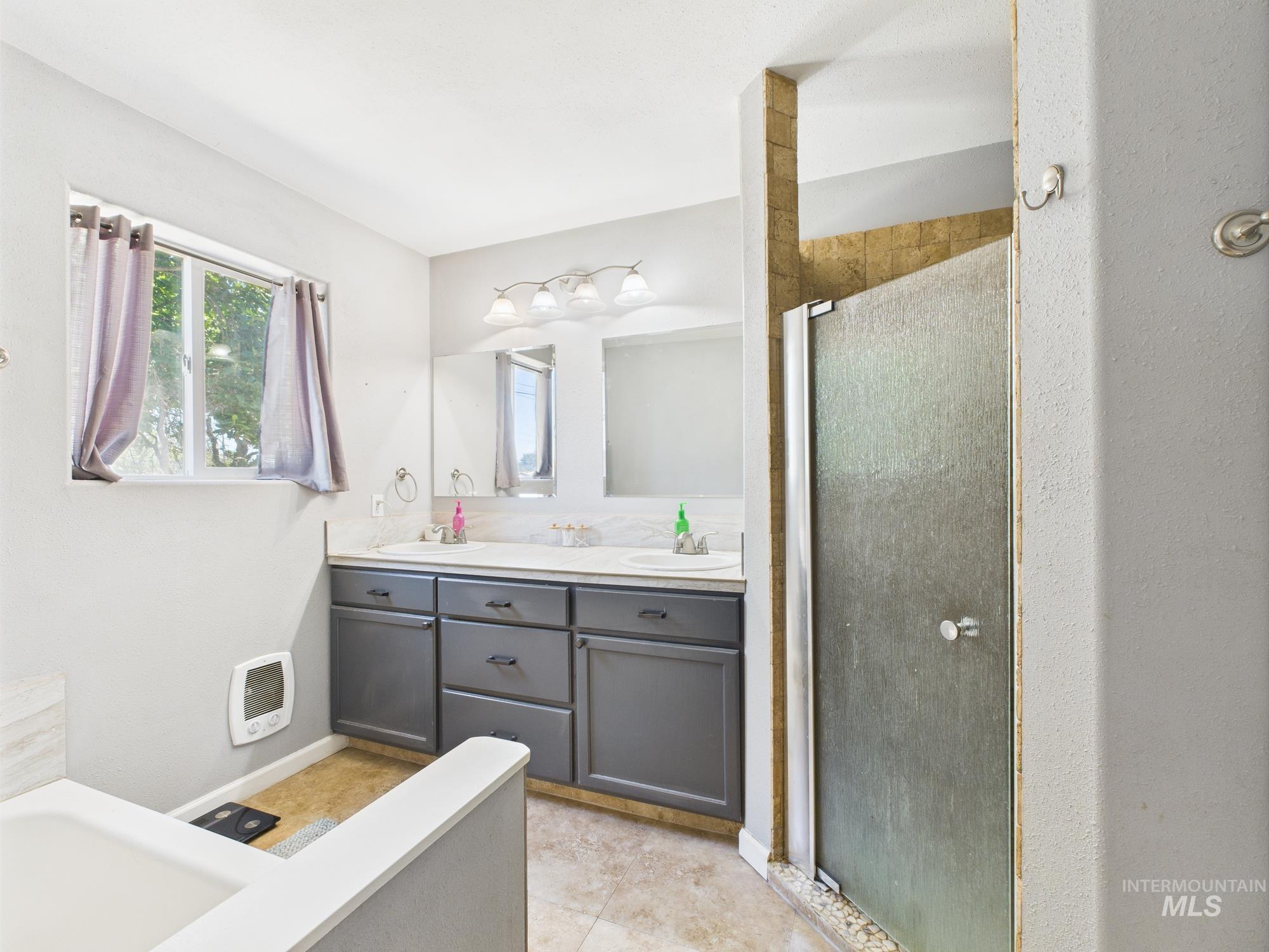 1428 Bryden Avenue Lewiston, ID 83501 - Photo 31 of 32 Bathroom with a shower stall, double vanity, a tub to relax in, heating unit, and tile patterned floors