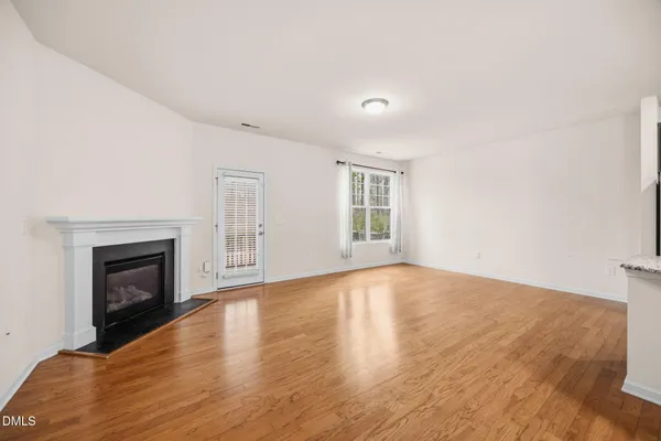 a view of empty room with wooden floor and fireplace