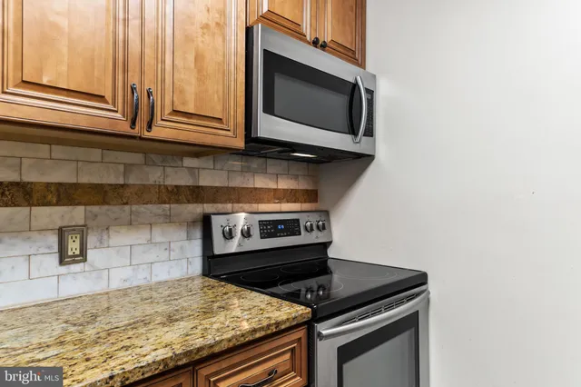a kitchen with granite countertop cabinets stove top oven and microwave