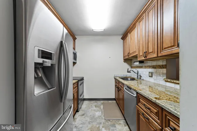 a kitchen with stainless steel appliances granite countertop a refrigerator a stove and a sink with cabinets