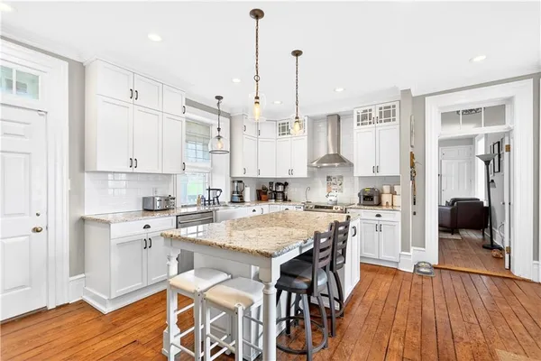 a kitchen with stainless steel appliances granite countertop a refrigerator a sink and wooden floor